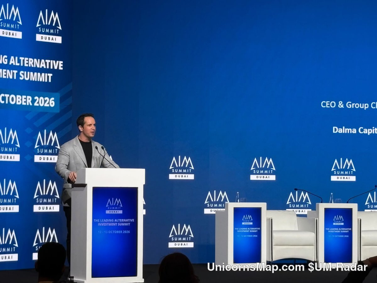 AIM Summit Dubai 2026 — opening keynote at the lectern under the AIM Summit Dubai LED wall, Jumeirah Emirates Towers