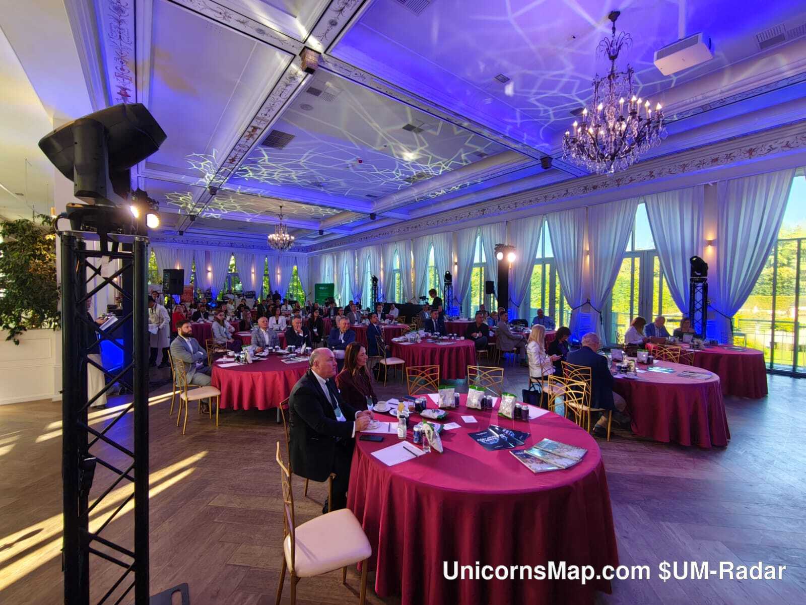 Family Business Forum 2026 — the ballroom at Pałac Mała Wieś set with round tables during the forum, palace windows and a stage lighting rig