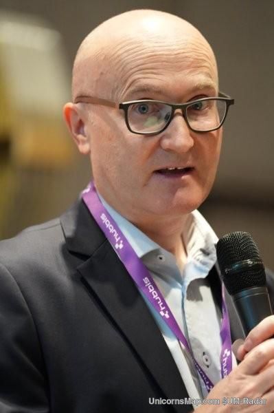 HNW Insurance Summit Zurich 2026 — a speaker addressing the room with a microphone, wearing a 1291 Group lanyard