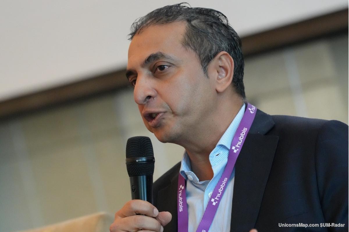 Hubbis Middle East Private Capital Forum 2026 — a speaker addressing the room with a handheld microphone, Hubbis lanyard worn