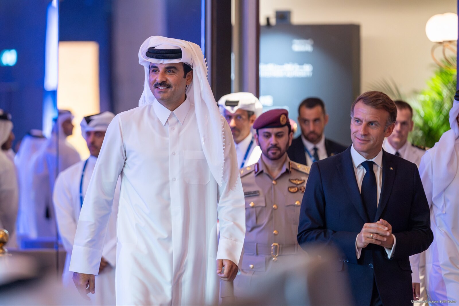 HH Sheikh Tamim bin Hamad Al Thani and President Emmanuel Macron walking through the summit venue in Doha on 21 October 2026, with officials and protocol staff behind them