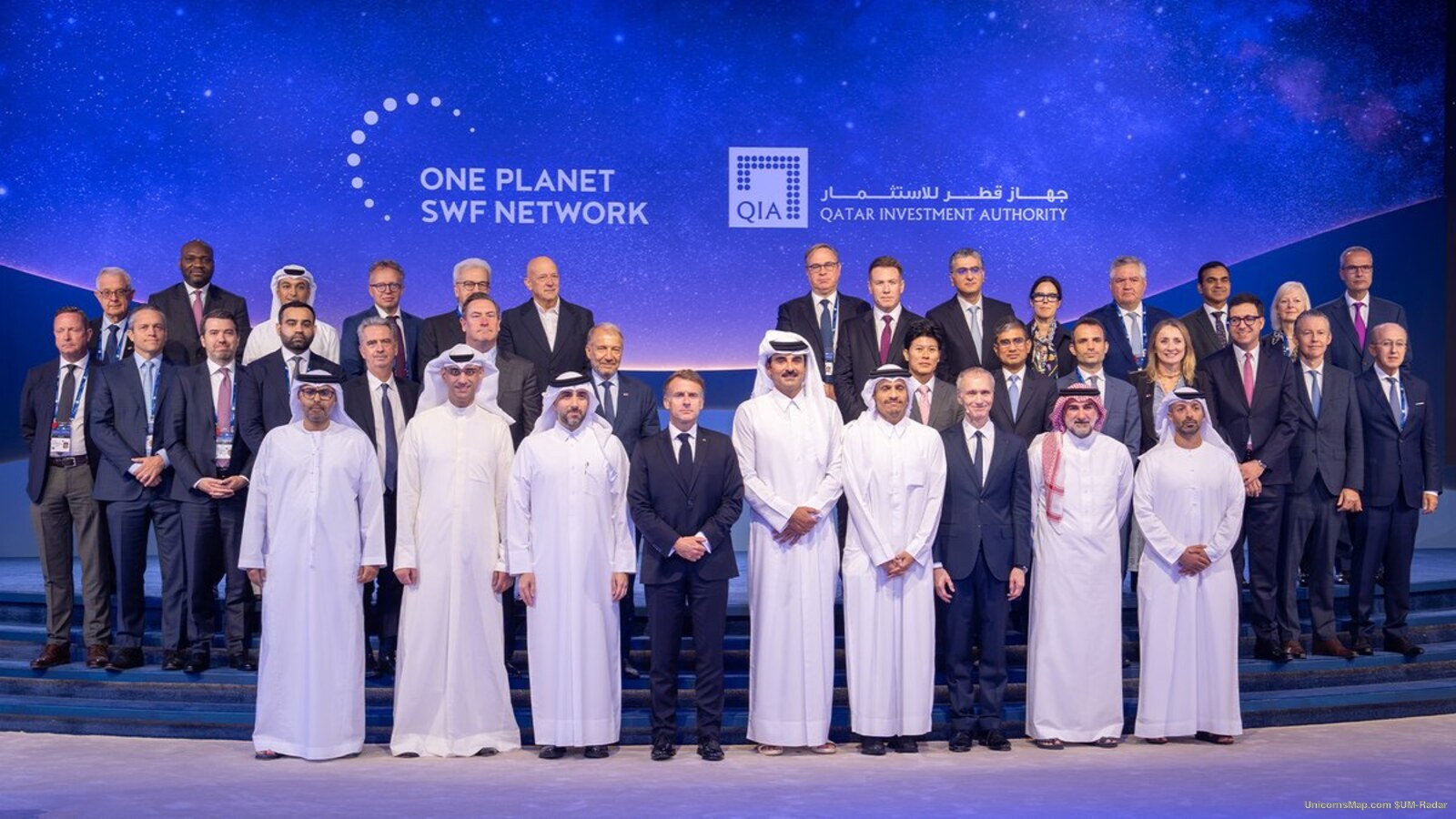 Official group photograph of the 9th annual One Planet Sovereign Wealth Funds CEO Summit, Doha, October 2026: about thirty-five participants in dark suits and Gulf national dress arranged on a low stage beneath a backdrop carrying the ONE PLANET SWF NETWORK wordmark and the QIA logotype
