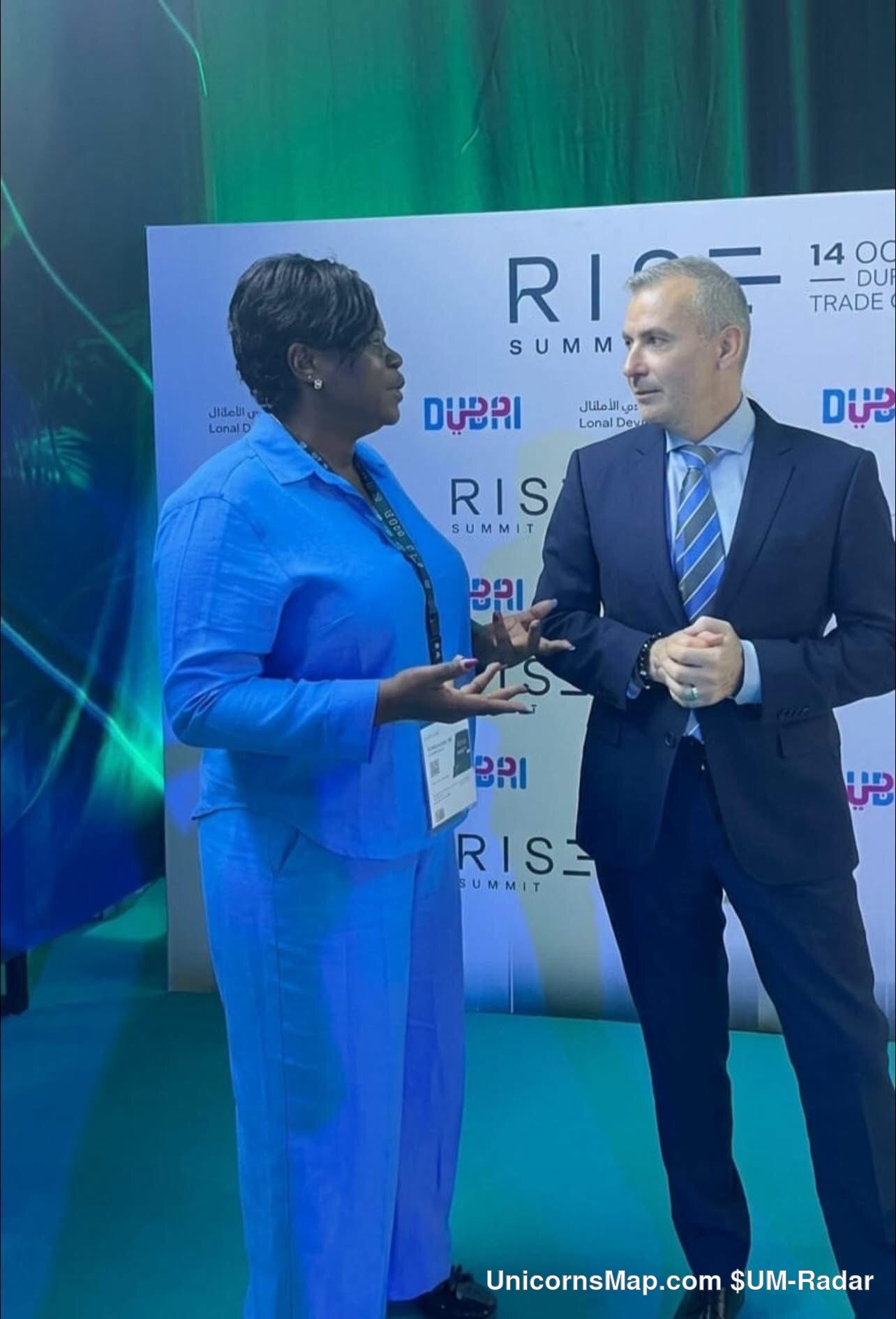 RISE Summit 2026 - two delegates in conversation against the event's own RISE SUMMIT / 14 OCT / DUBAI TRADE CENTRE backdrop